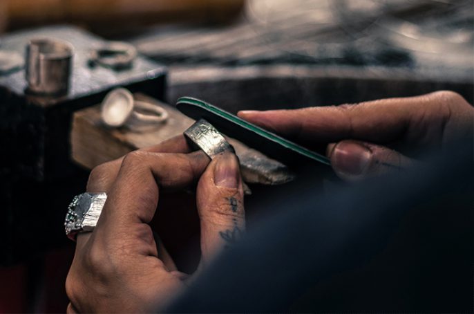 Close-up of hands of jewellery designer filing a silver ring