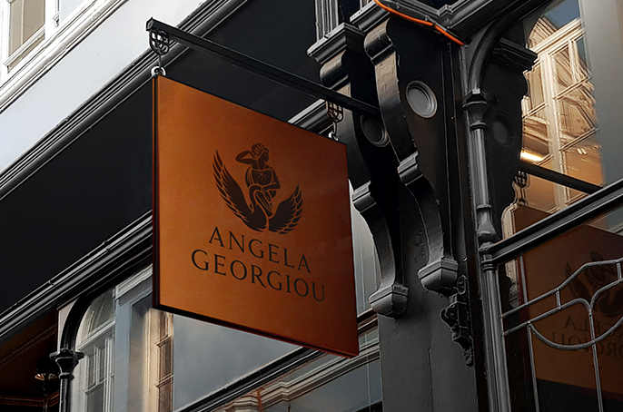 Bronze coloured hanging sign above shop entrance showing jewellery designer logo