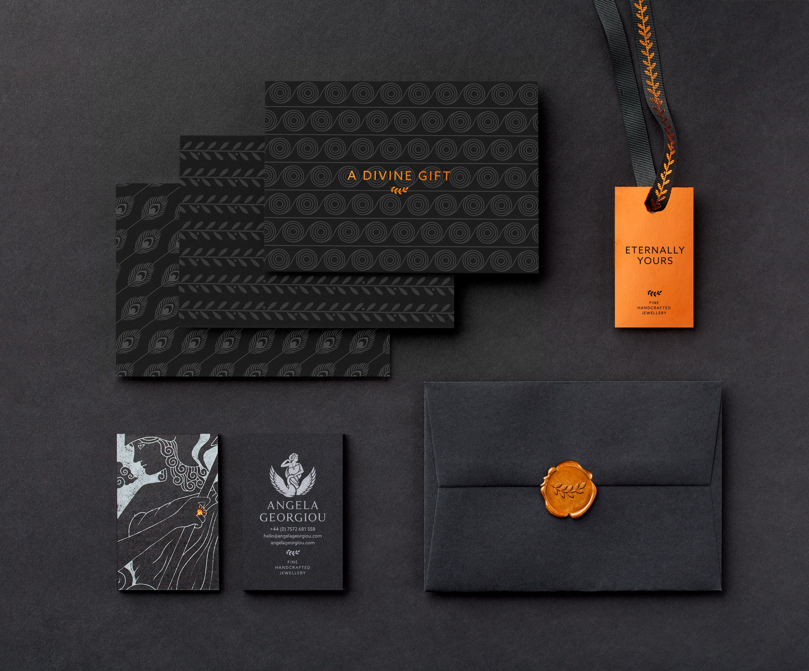 Selection of branded stationery against a dark background including three postcards, business cards, envelope with wax seal and gift label with ribbon