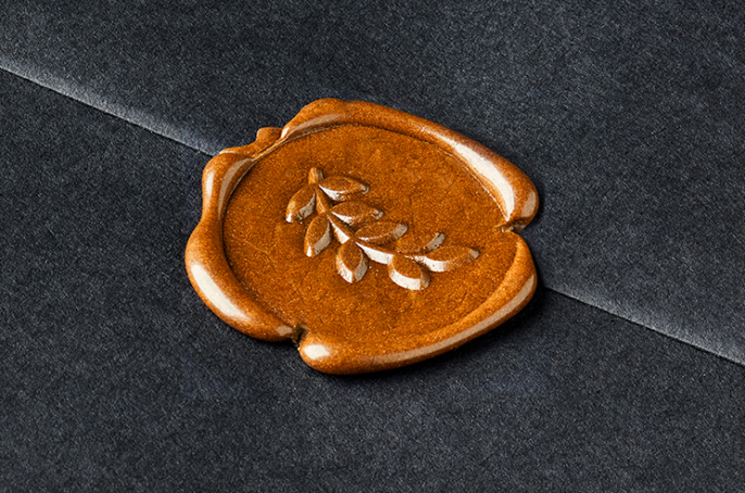 Close-up of a bronze coloured wax seal with olive branch detail