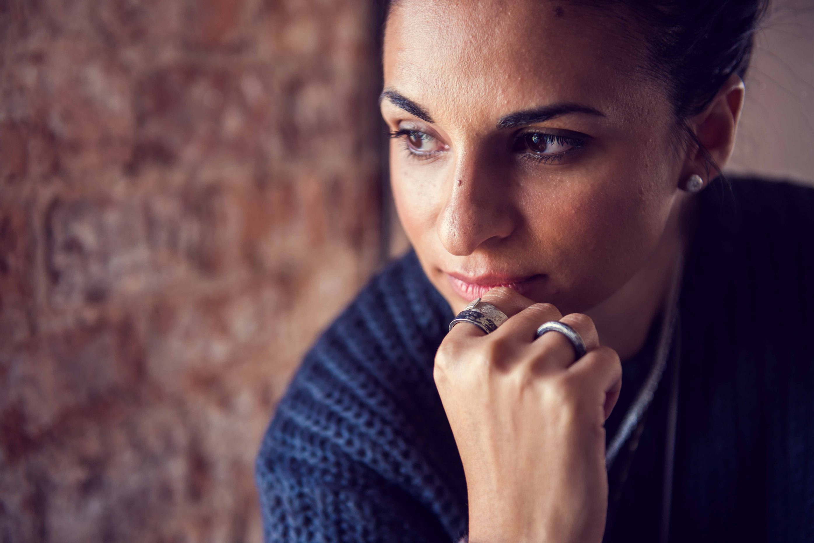 Photo of woman's face with hand resting on chin showing silver rings