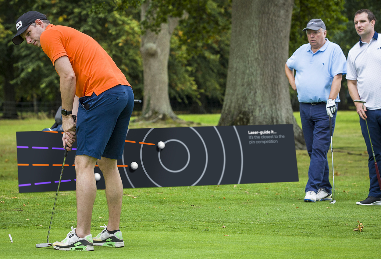 Man on putting green playing shot next to event branded banner