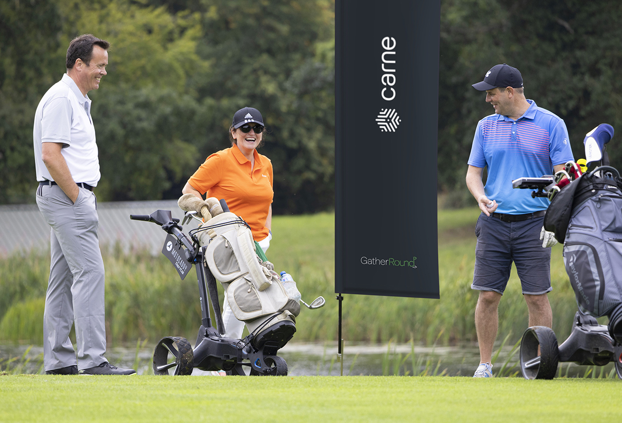 Group of golfers stood next to event branding on flag