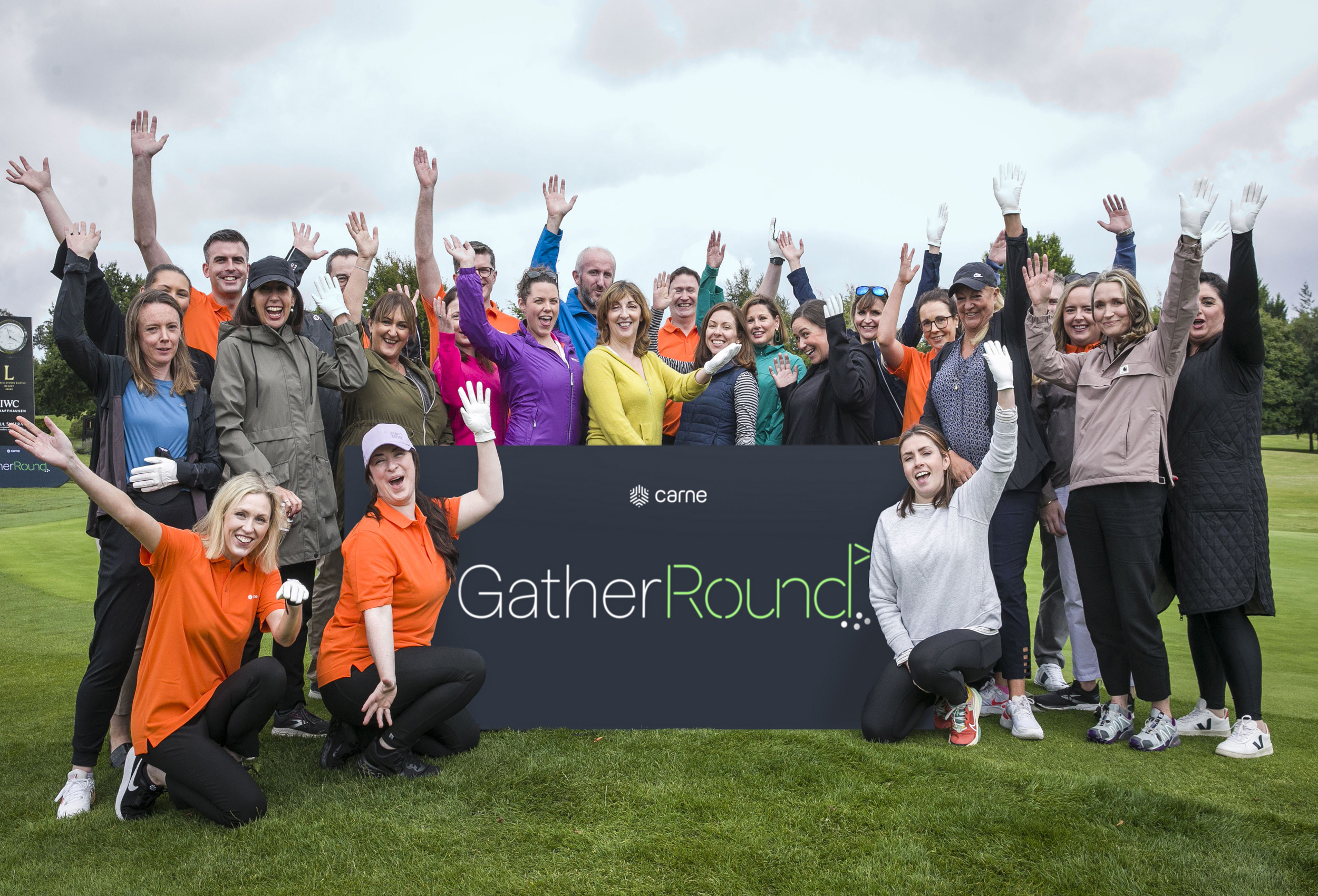 Large group of people cheering alongside branded golf event signage