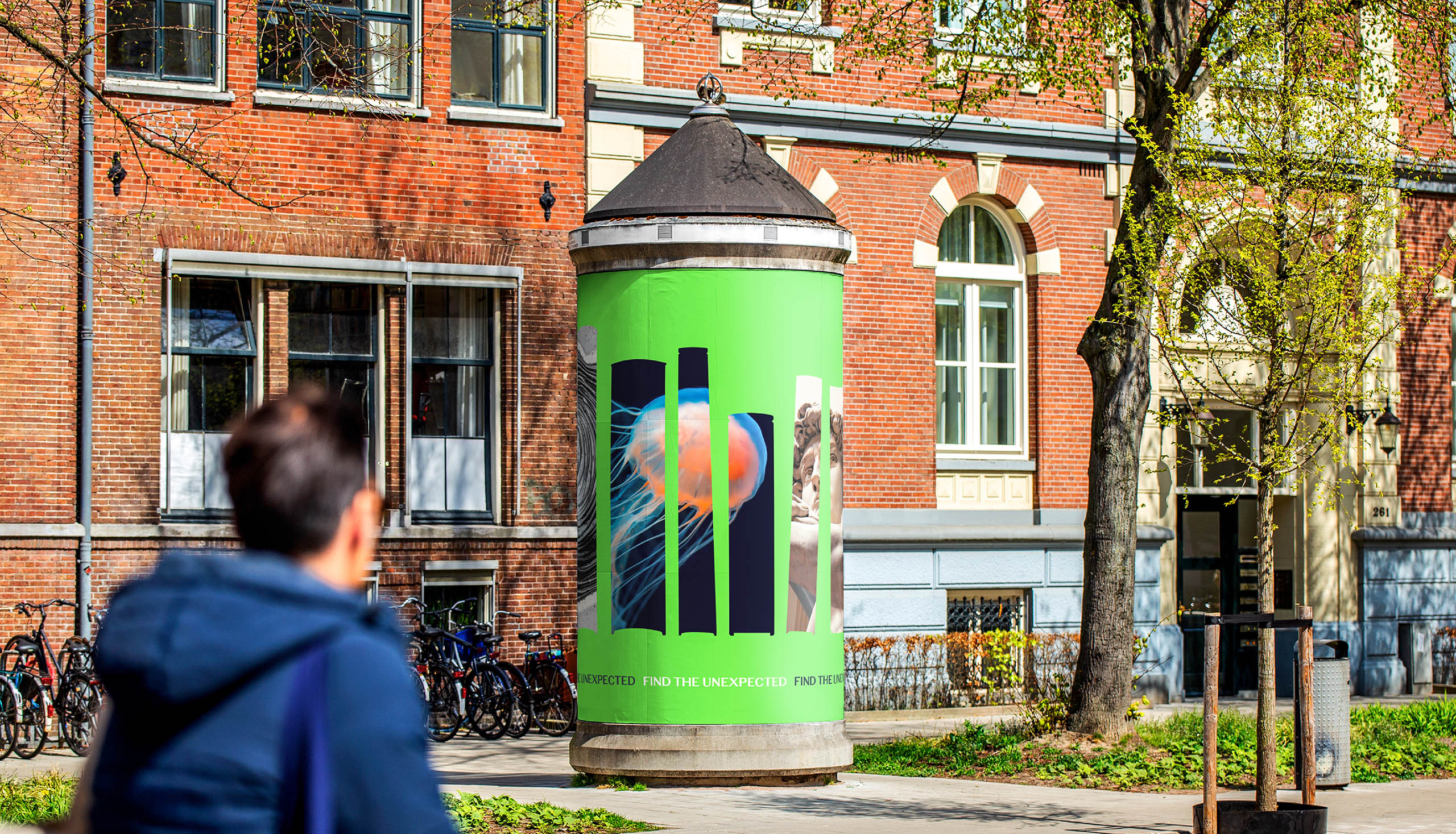 Advertising pillar in city street showing branded poster design that uses book silhouettes to reveal a mix of images within